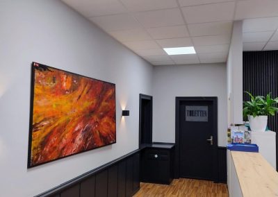 Abstraktes Kunstwerk mit warmen Farben an der Wand eines Flurs in einem Gebäude.